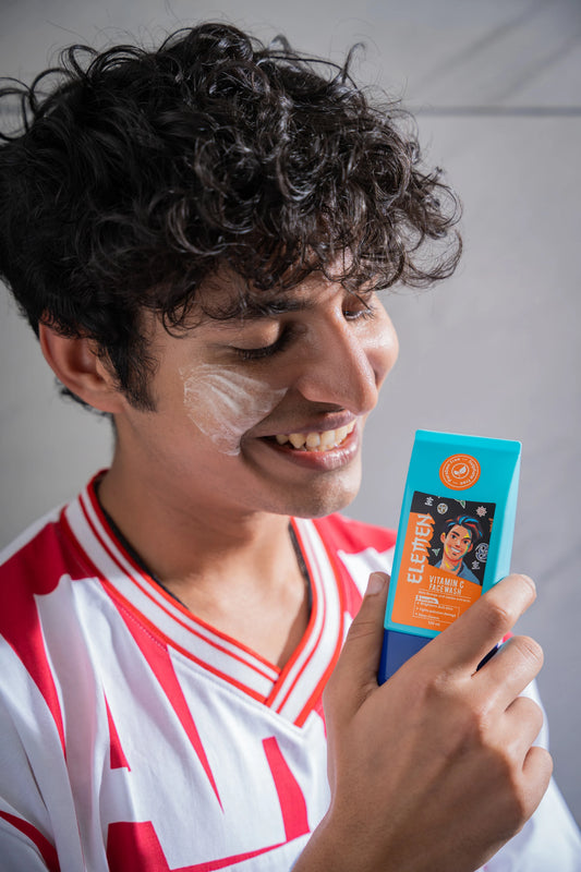 Man holding a vitamin c facewash product with a visible brand logo against a neutral background